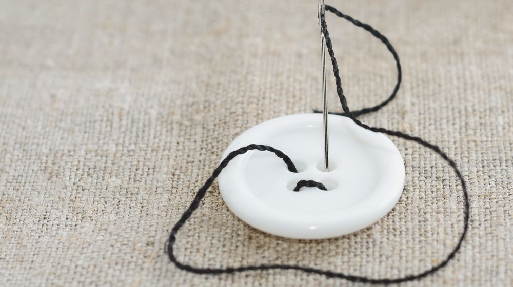 needle black thread white sewing button | How To Sew A Button Like An Expert | Featured